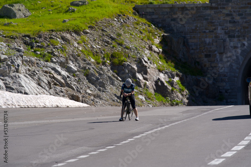 Exhausted woman racing cyclists just arrived at summit of Swiss mountain pass Susten on a sunny summer day. Photo taken July 13th, 2022, Susten Pass, Switzerland.
