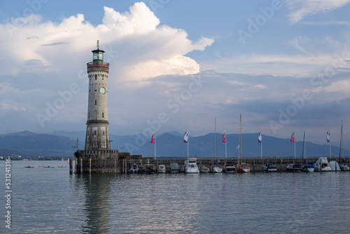 White big lighthouse on the Bodensee Lindau Germany with pier and flags reflecting in the water