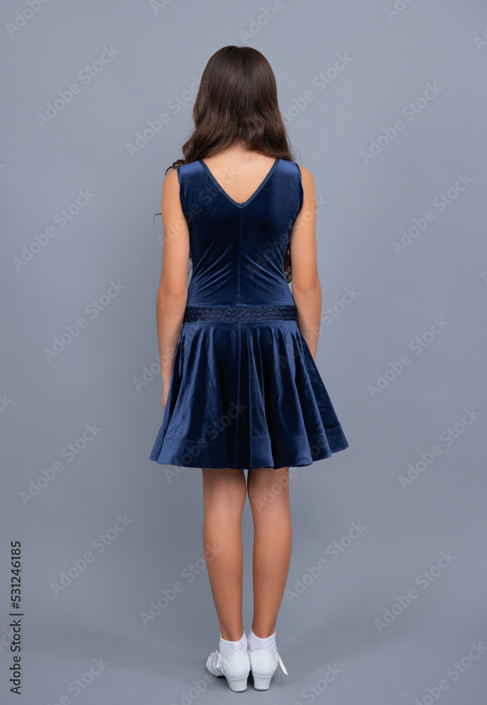 Fototapeta premium Full length of teenager child in ball dress. Back view of young graceful teenager child in dress isolated on gray background.