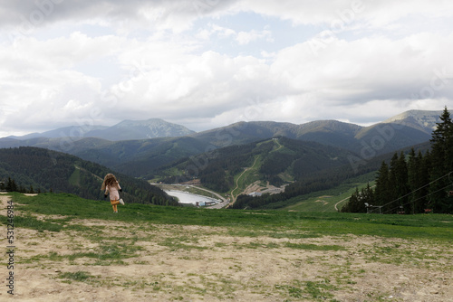 Tourist young girl child on the top of the Carpathian mountains Ukraine Bukovel. Vacation concept with panoramic view.