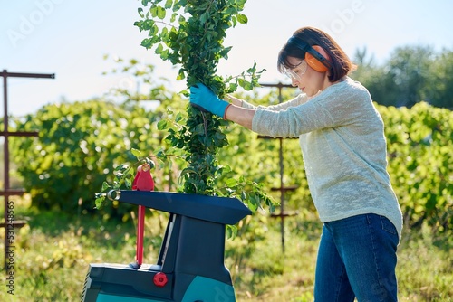 Woman using electric garden shredder for branches and bushes photo