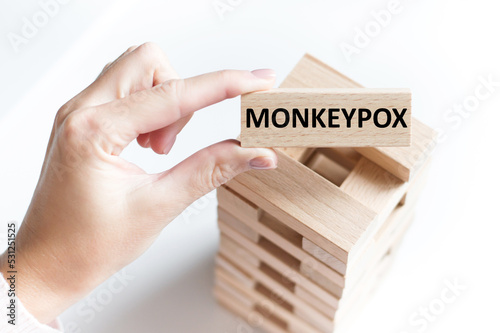 MONKEYPOX VIRUS text on wooden cube in a person's hand on a light table background photo