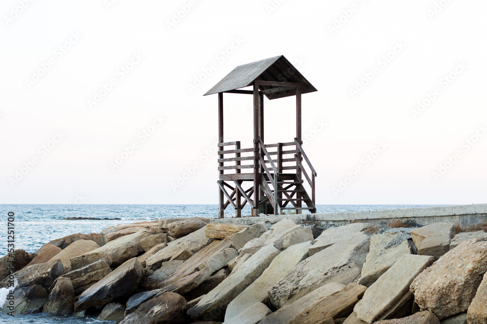 Mediterranean beach with wooden lifeguard chair in sunset time