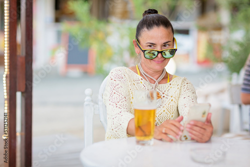 Portrait of beautiful young woman drinking beer at beach cafe and enjoying summer day