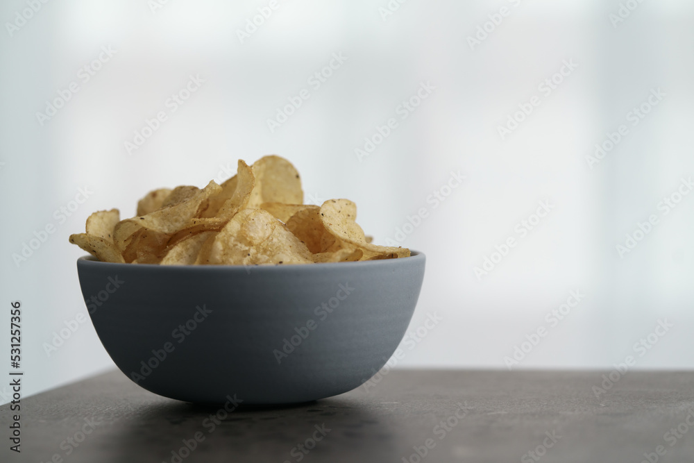 Organic potato chips with black pepper in blue bowl on counterttop Organic potato chips with black pepper in blue bowl on counterttop