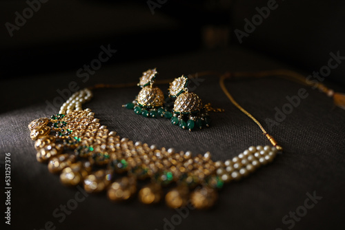 Gold Necklace with Green Gems in Black Background