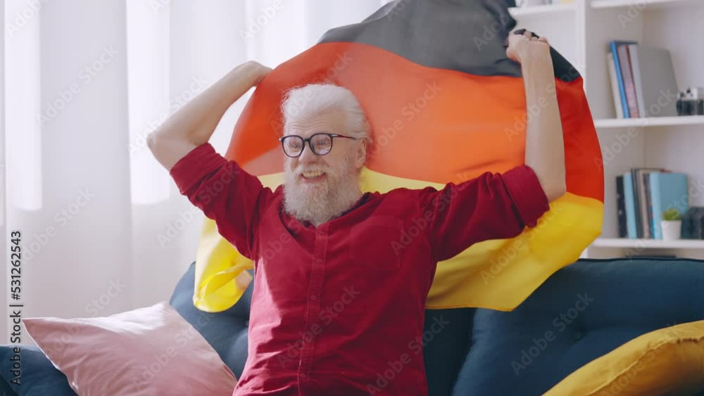 Happy grandpa cheering for German sport team, nice fan watching game at home Happy grandpa cheering for German sport team, nice fan watching game at home