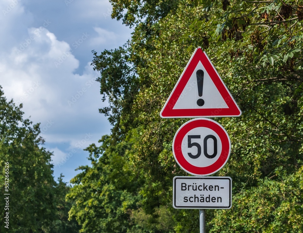 Ein Warnschild am Straßenrand warnt vor Brückenschäden und man darf nur 50 km/h fahren