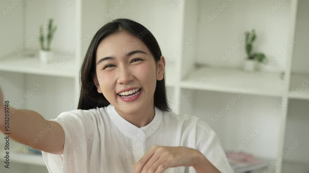 Happy asian teen girl waving hand using smartphone app enjoying online virtual chat video call with friends.