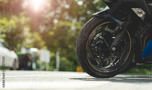 Part of a motorcycle wheel, tire, parked on a beautiful road. motorcycle in a sunny motorbike on the road riding.with sunset light. copyspace for your individual text.