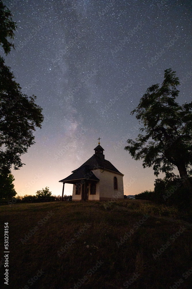 Fototapeta premium Milchstraße Sternenhimmel über Kirche Kapelle Kleine Kalmit im Sternenpark Pfälzerwald