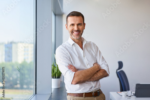 Portrait of smiling mid adult businessman standing at corporate office photo