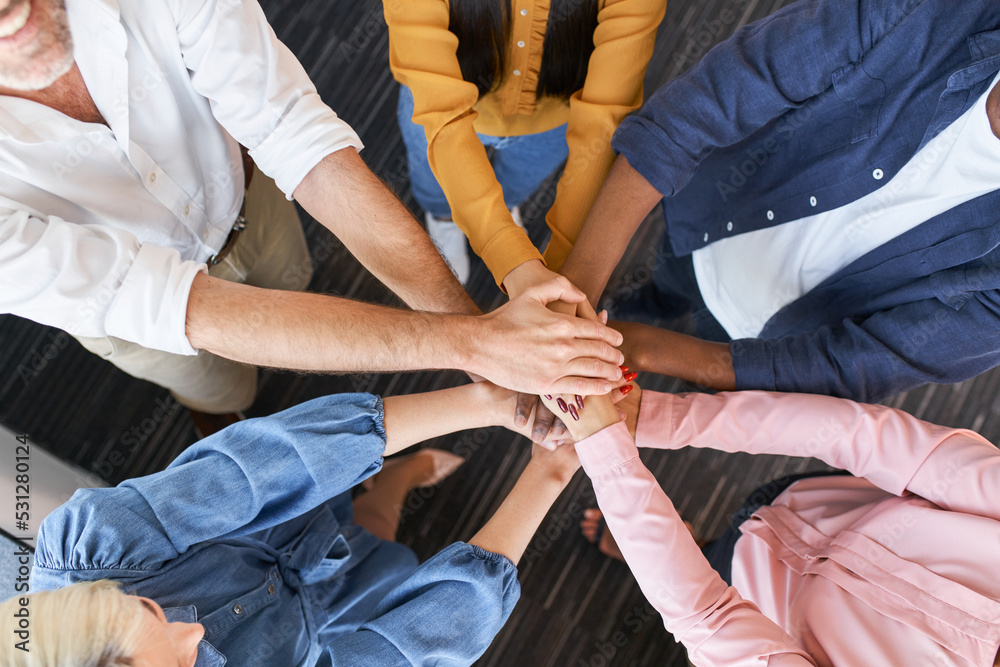 Fototapeta premium Close up of coworkers stacking hands together at office. Business people team building concept.