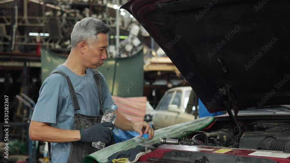 Drinking water. Tired hot wiping sweat. Senior man car machanic worker working hard at Auto car truck mechanic workplace. Drinking water. Tired hot wiping sweat. Senior man car machanic worker working hard at Auto car truck mechanic workplace.