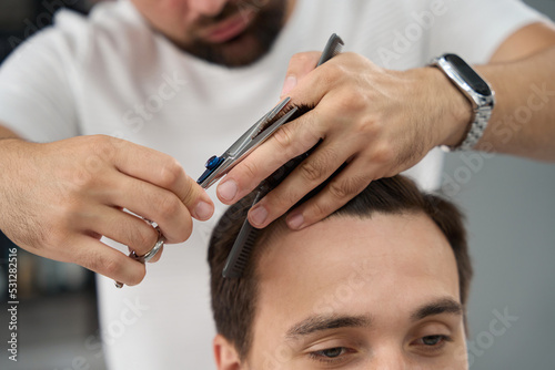 Barbershop worker carefully performing a fresh haircut for a man