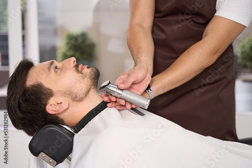 Good-looking guy enjoying professional hair trim at barbershop