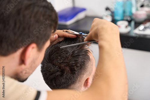 Hard-working hair salon worker giving guest a haircut
