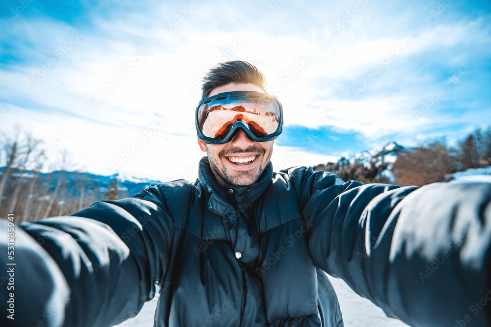 Young man taking selfie picture with smart cell phone hiking mountain on snowy slope - Happy skier having fun in ski resort vacation - Winter lifestyle, extreme sport and happy people concept Young man taking selfie picture with smart cell phone hiking mountain on snowy slope - Happy skier having fun in ski resort vacation - Winter lifestyle, extreme sport and happy people concept