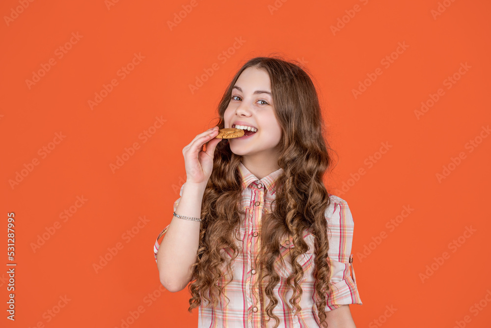 teen girl biting oatmeal cookies on orange background teen girl biting oatmeal cookies on orange background