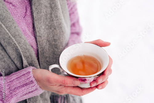 Winter tea in a cup on the snow. Winter atmospheric background with coffee in nature. Sunny frosty morning.