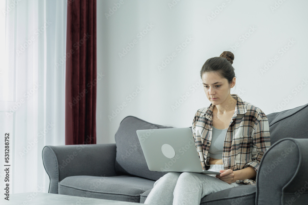 Fototapeta premium The girl works from home at the computer. I thought about my future. Online shopping in your free time.