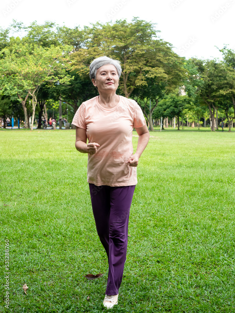 Portrait of mature asian woman 60s wearing sports clothing jogging in the park outdoor.