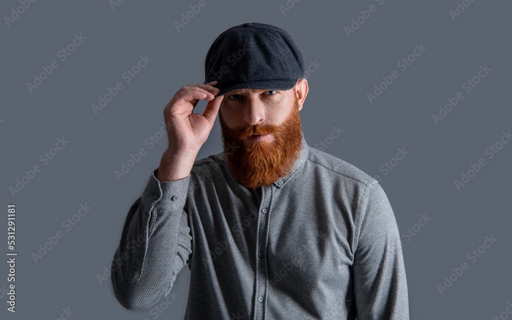 Irish man adjusting cap studio. Portrait of bearded man. Serious man with unshaven face beard