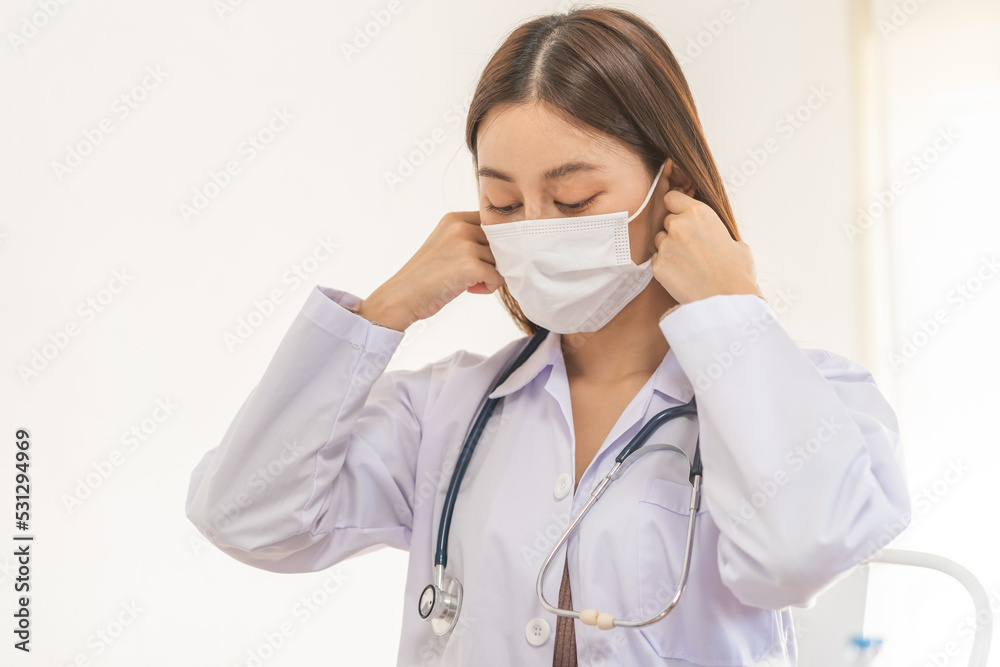 Doctor or physician asian young woman, wearing white coat, stethoscope and medical face mask to protect disease, prevention virus pandemic of covid-19, portrait isolated on background. healthcare. Doctor or physician asian young woman, wearing white coat, stethoscope and medical face mask to protect disease, prevention virus pandemic of covid-19, portrait isolated on background. healthcare.
