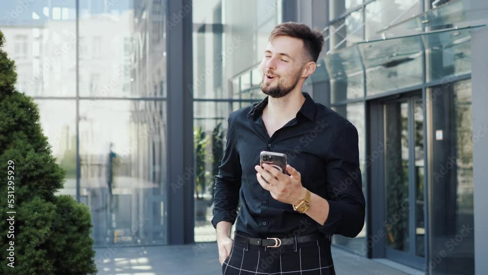 Excited business man doing online shopping, buying with a credit card or paying bills on a phone. Happy, smiling businessman making a wireless purchase or payment outdoors in the city. Banking money.