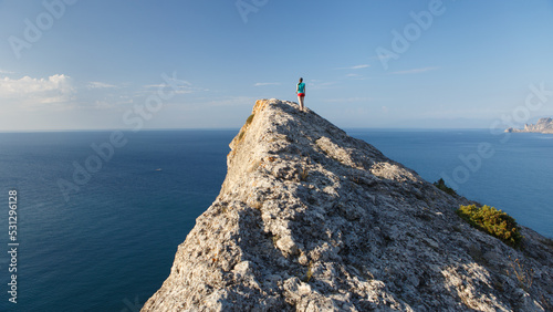 A lonely figure of a walking girl on a narrow triangular cliff on the Southern coast of Crimea