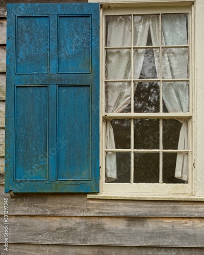 Old wooden window and shutter on weathered clapboard clad wall photo