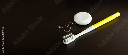 Dental floss and toothbrush on a black background. Dental care.