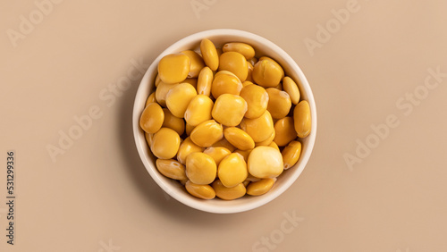 salted lupins in white bowl standing on beige background, Flay lay