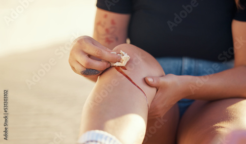 Knee injury and person cleaning blood wound with tissue to stop bleeding for healing and recovery. Self care hygiene after accident with torn and sore skin on leg for infection prevention. photo