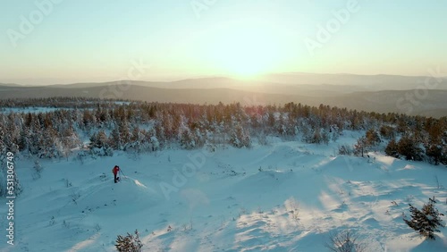 top view of a man with camera on the tripod capturing the photo of sunset in winter landscape. standing on the top of the mountain