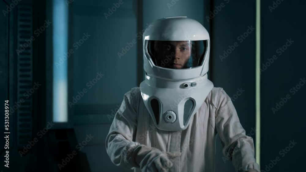 Portrait of an astronaut wearing a helmet in a spaceship. A confident young male astronaut walks up and looks into the camera. Portrait of an astronaut wearing a helmet in a spaceship. A confident young male astronaut walks up and looks into the camera.