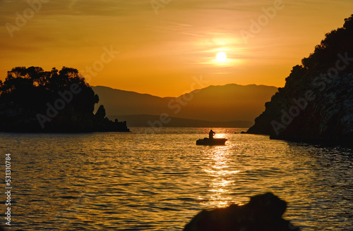 Blick auf die Silhouette eines kleines Fischerbootes morgens w  hrend des Sonnenaufgangs in der Bucht von Agios Spiridon auf Korfu  horizontal 