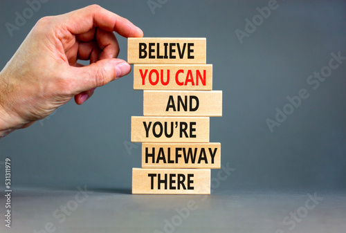 You can symbol. Concept words Believe you can and you are halfway there on wooden blocks on a beautiful grey table grey background. Businessman hand. Business motivational and you can concept.