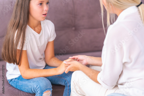 mom or psychologist, talks to child holding hands, supporting at home, expressing emotions. an anxious teenage girl listens to psychologist at meeting talking about her problems. Successful therapy