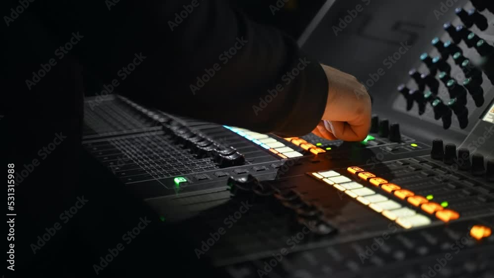close-up of a male hand on a mixing console. sound engineer works in the club. concert at the stadium. backstage of the event. sound engineer adjusts the volume level. monitors screens in the studio