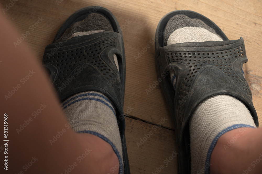 Human feet in socks and slippers, torn slippers on a human foot.