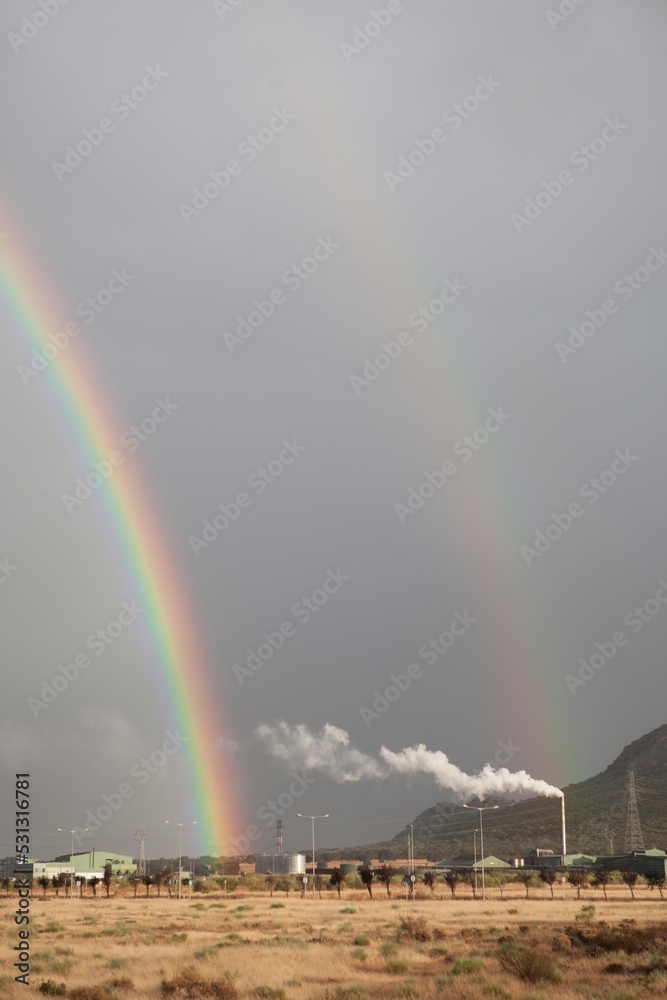 Double rainbow rising over an industrial area. Primary and secondary rainbows are visible Double rainbow rising over an industrial area. Primary and secondary rainbows are visible