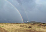 Double rainbow rising over an industrial area. Primary and secondary rainbows are visible