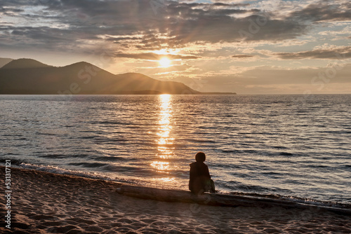 Barguzinsky Bay of Lake Baikal, Russia. Colorful sunset. Silhouette of sitting person on beach. photo