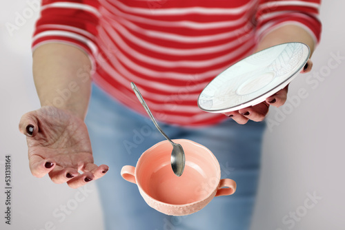 A female in red and white stripy shirt dropping teacup with tea and spoon, selective focus photo