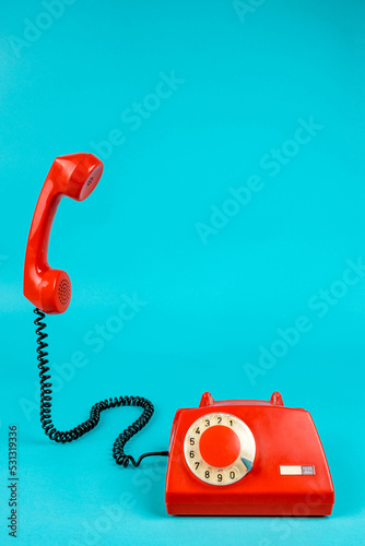 Old phone on a blue background. Antique phone with a tube. Red telephone with a receiver. Retro telephone