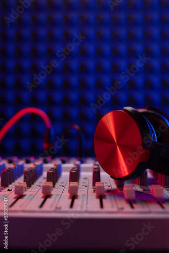Headphones on sound mixer with faders near acoustic foam. Music concept