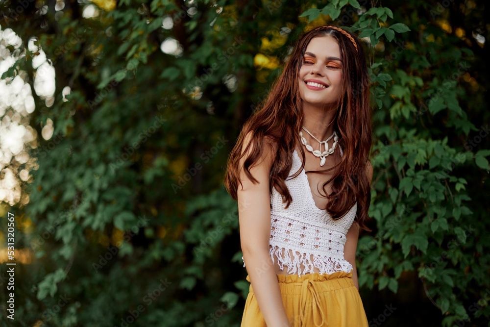 A woman in eco-friendly clothing in a hippie look dances in nature in the park and smiles at the world. The concept of harmony with the body and the surrounding nature