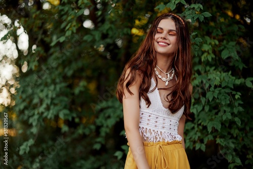 A woman in eco-friendly clothing in a hippie look dances in nature in the park and smiles at the world. The concept of harmony with the body and the surrounding nature