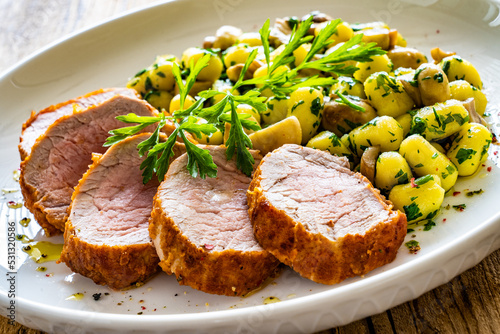 Fried pork loin with gnocchi and mushrooms on wooden table
 photo